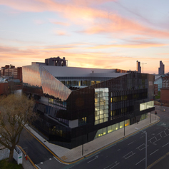 Exterior of The National Graphene Institute (NGI) building with colourful sunset