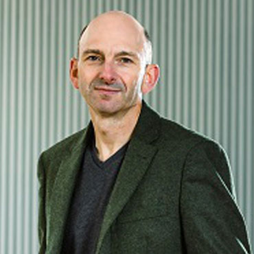 Profile of man smartly dressed and smiling at the camera
