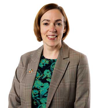 Profile of a woman in a brown jacket smiling
