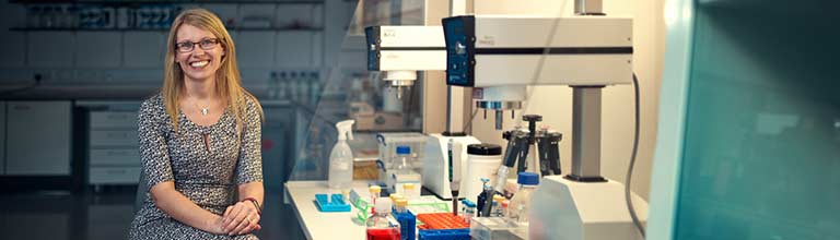 Professor Aline Miller sat in lab looks towards camera