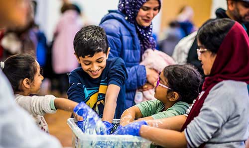 Group of primary school age children putting their hands into a bowl
