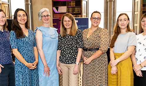 Seven ladies stood in a line, smiling and looking towards the camera.