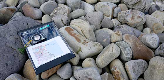 A compass and small map laying on some rocks