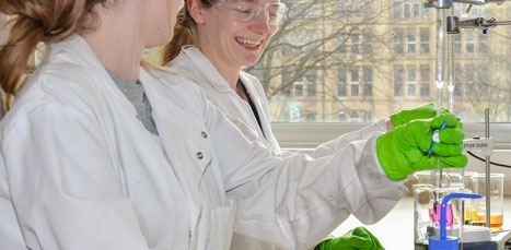 Two lab researchers smiling while attending beacons of liquid