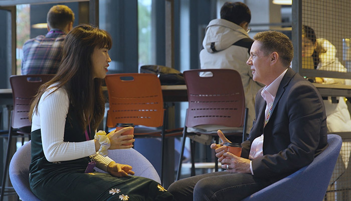 A postgraduate researcher talks to supervisor over a coffee