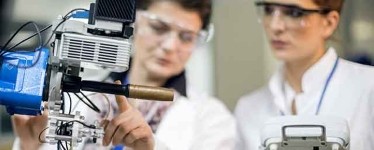 Two researchers in a laboratory examining advanced materials using specialist scientific equipment.
