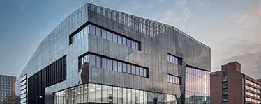 A cubed shaped black glass building with a slanted roof