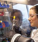 Female student wearing glasses while operating lab equipment