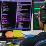 Male at desk looking at code on monitor