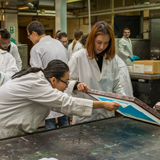 Two females wearing white lab coats and screen printing