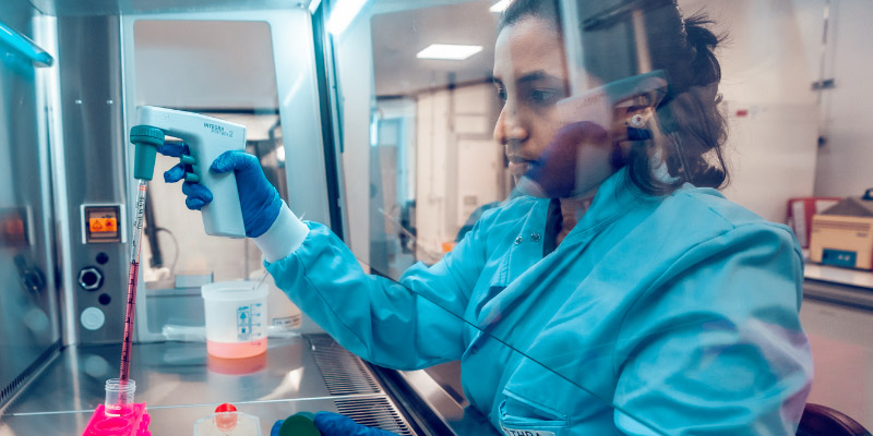 Researcher working in a laboratory using pipetting equipment.