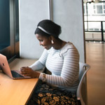 Student sitting by a window using a laptop.