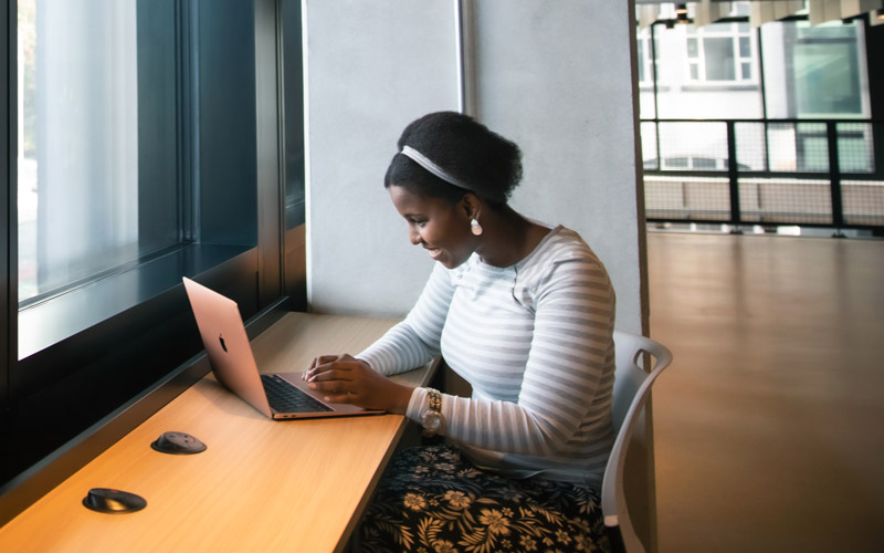 Student sitting by a window using a laptop.