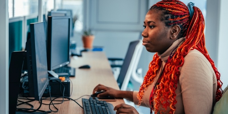 A researcher at The University of Manchester with red hair working on a computer in an office.
