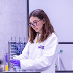 A student wearing a lab coat working in a laboratory.