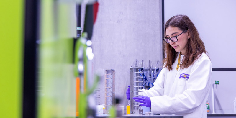 A student wearing a lab coat working in a laboratory.