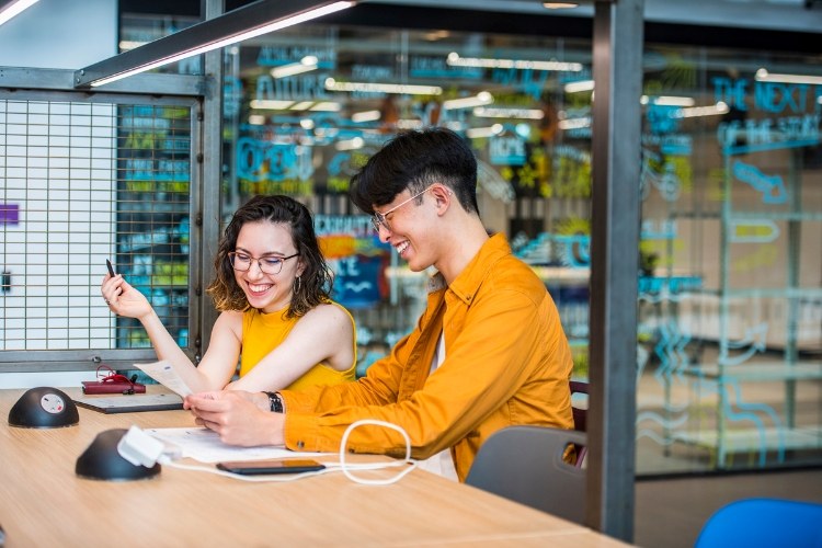 Two students laughing while working together in the University's Nancy Rothwell Building.