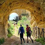 Students walking outside on a path arched with tunnels of mountain rock